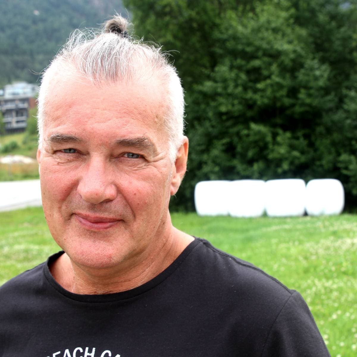 Alf Steinhovden ute på jordet, med rundballer i bakgrunnen